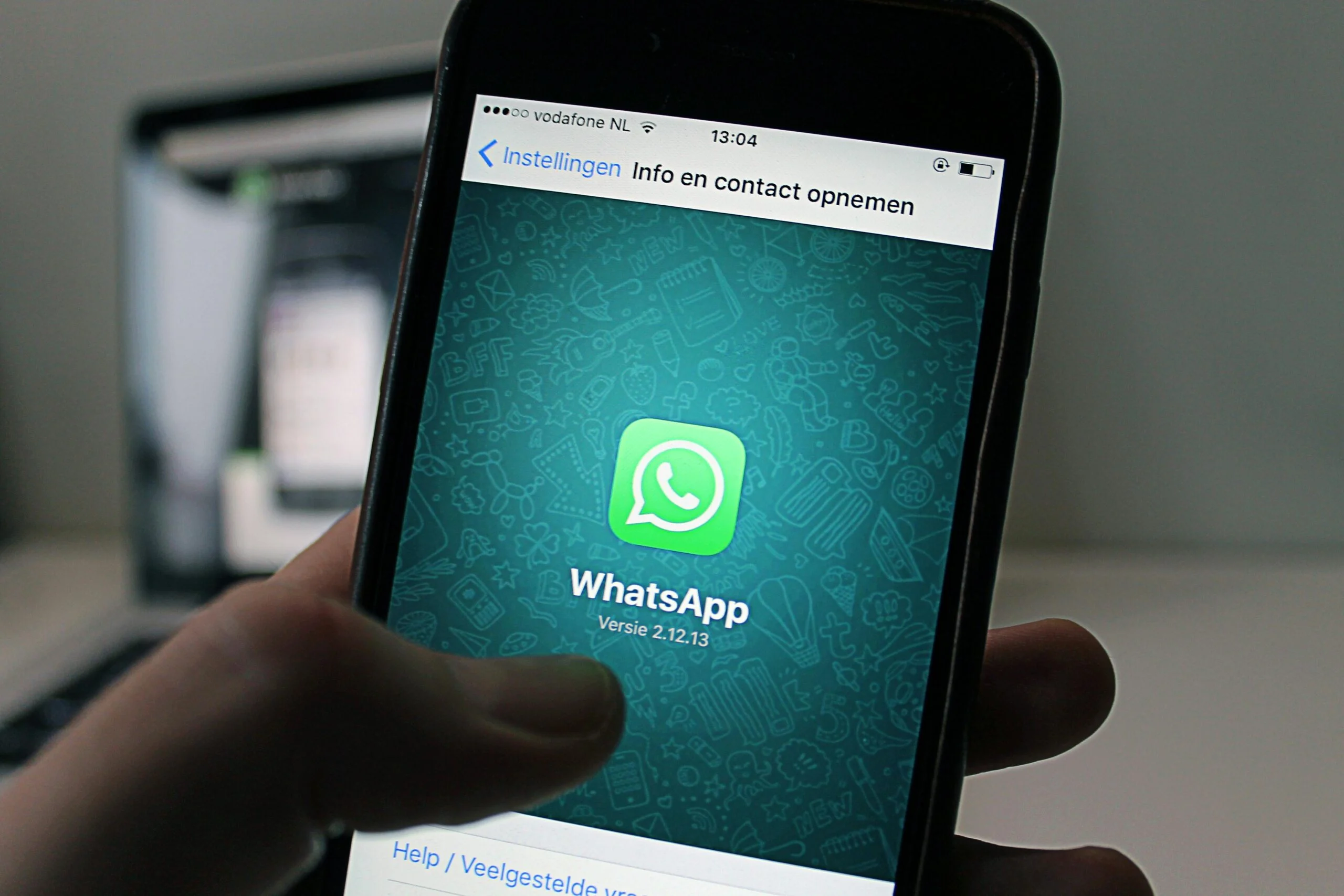 Hand holding a smartphone showing the WhatsApp logo on its screen