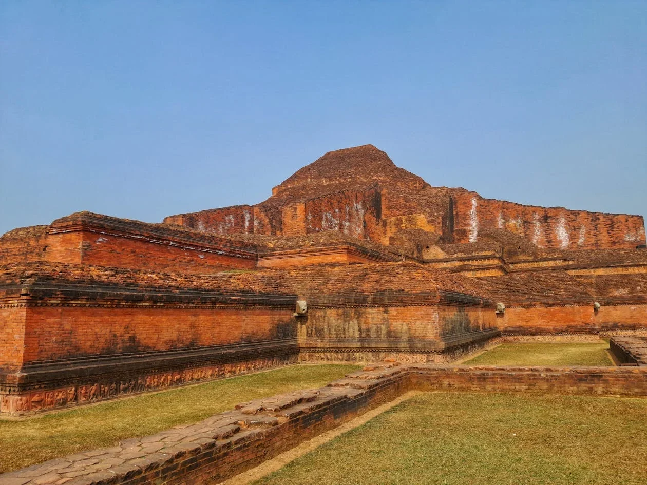 Red brick ruins of an ancient stepped temple structure under a clear blue sky
