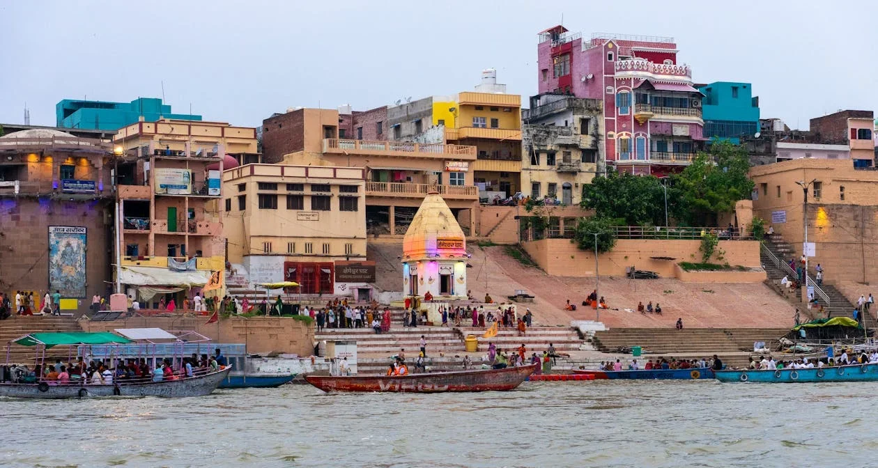 Boats on the Ganga in front of crowded ghats and colourful buildings in Varanasi
