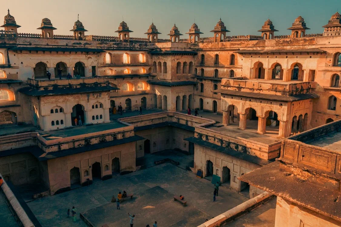 Sandstone fort courtyard with arched galleries and small domed turrets glowing in warm evening light