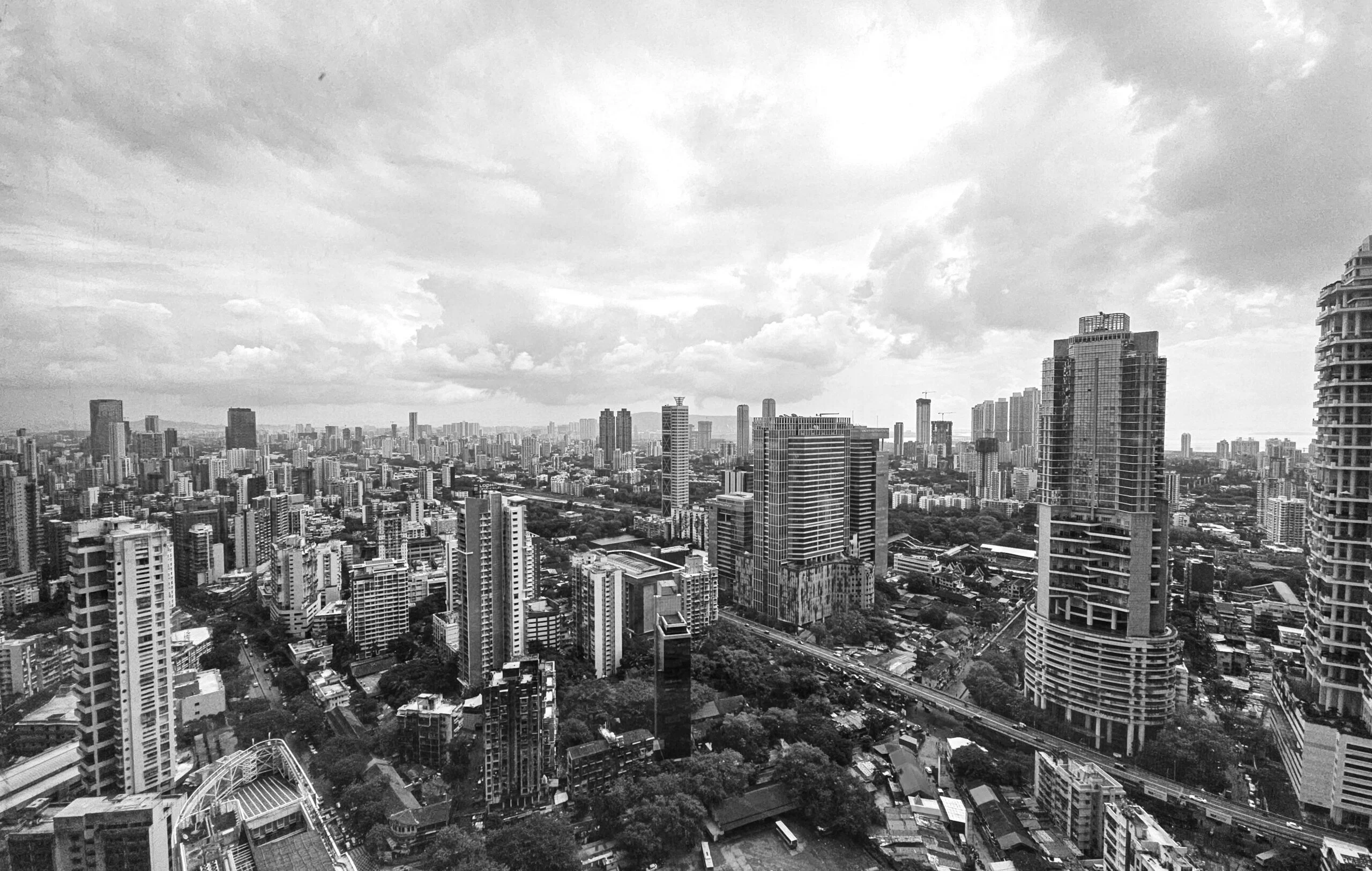 Black and white view of a dense city skyline of high-rise towers under a cloudy sky