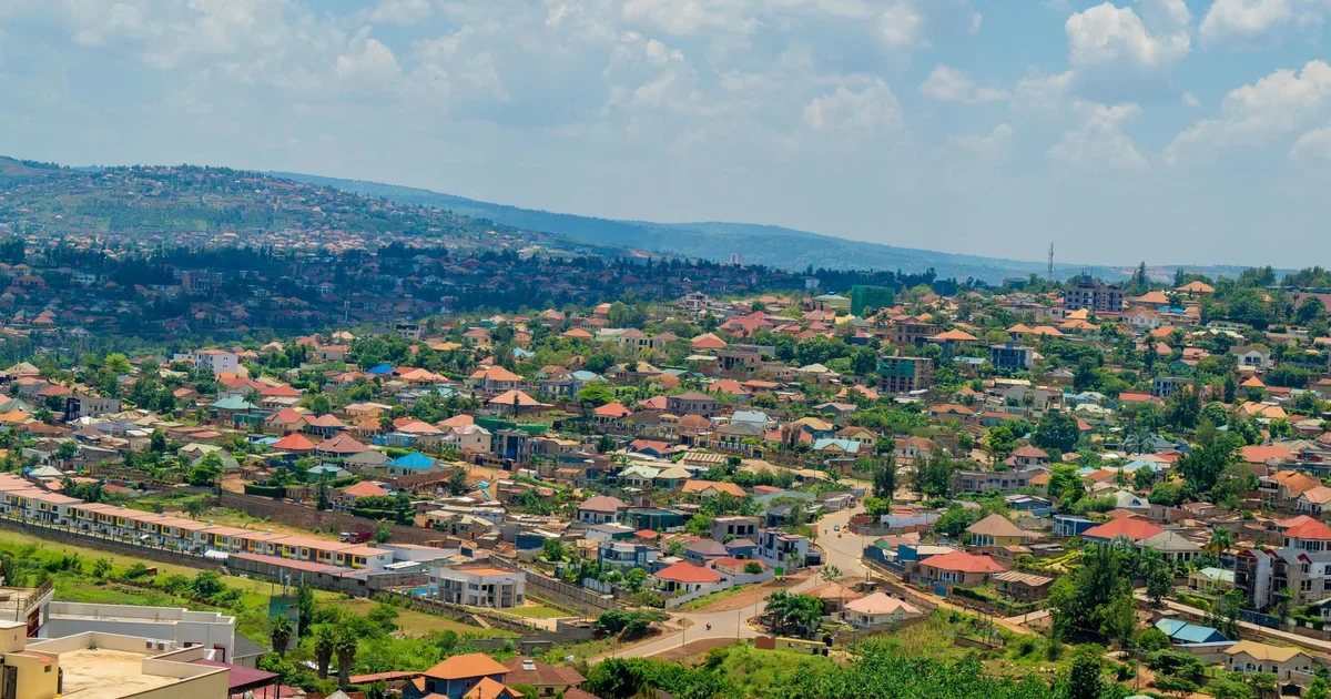 Hillside city of red-roofed houses and trees under a partly cloudy sky