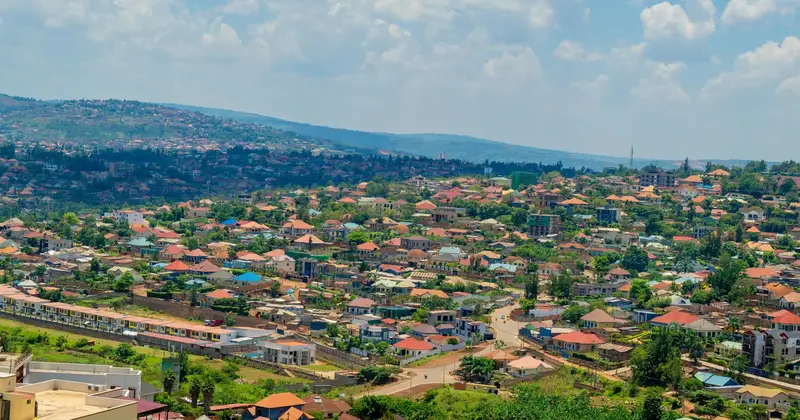 Hillside city of red-roofed houses and trees under a partly cloudy sky