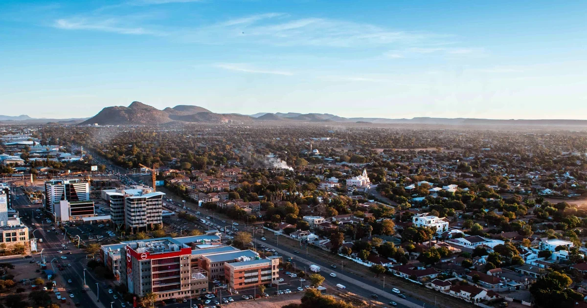 Aerial view of a city with office buildings, tree-lined streets and low hills on the horizon at sunrise
