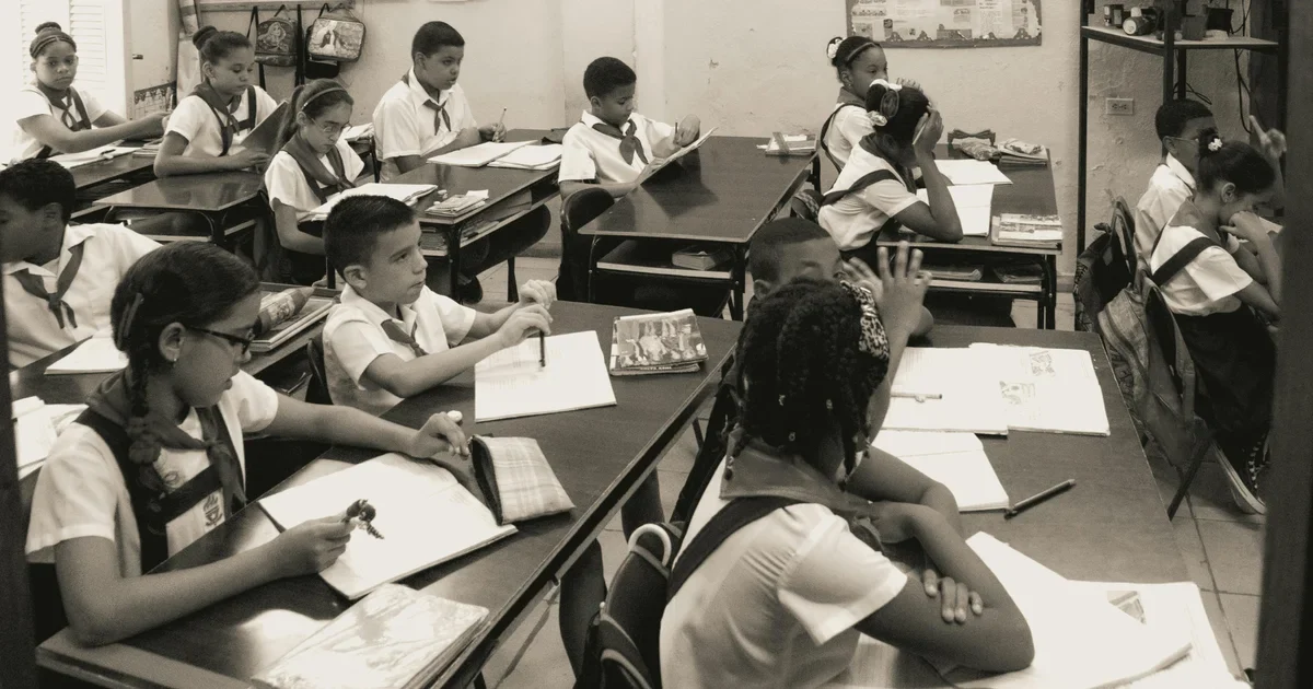 Sepia photo of schoolchildren in uniforms and neckerchiefs working at shared desks in a classroom
