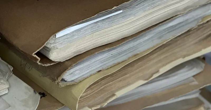 Stack of worn paper files and records bound in brown covers