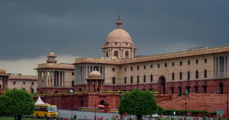 Government building with a red sandstone dome and colonnades under a dark stormy sky