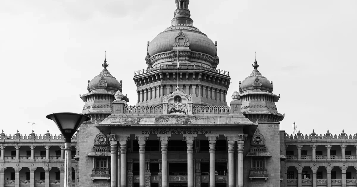 Black and white view of the domed Vidhana Soudha government building in Bengaluru with a street lamp in front