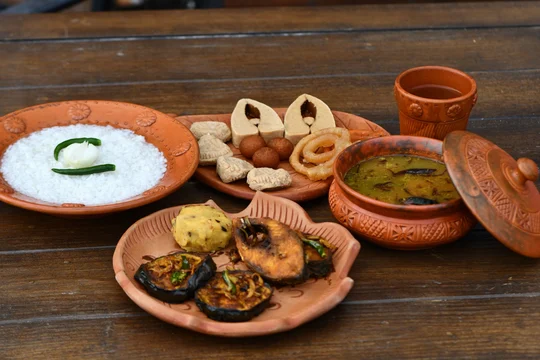 Bengali meal of rice, fried fish, dal, begun bhaja and sweets served in clay dishes
