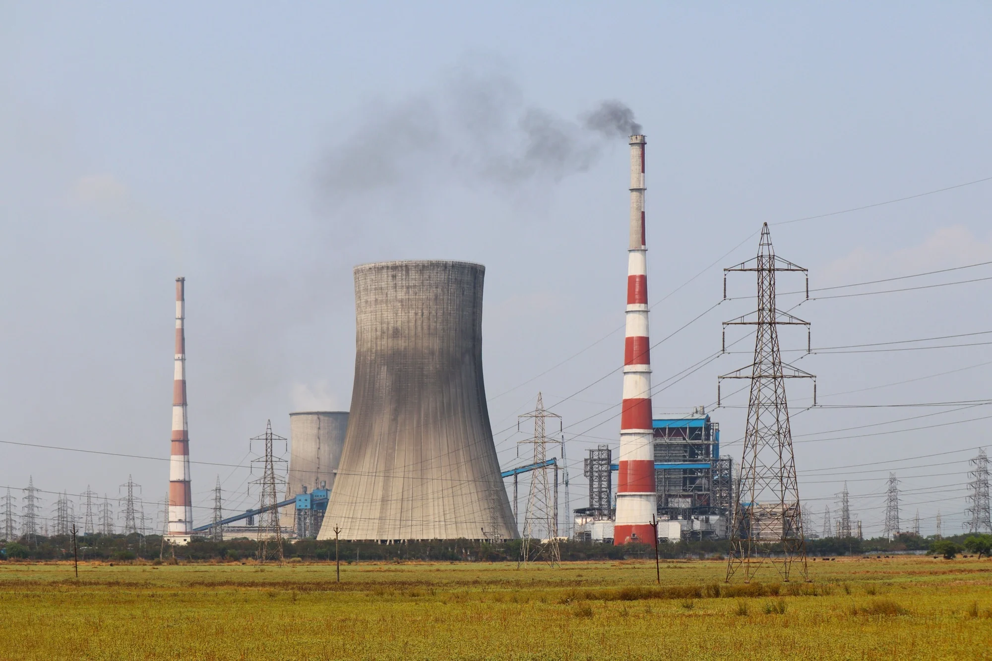 Coal power plant chimneys and a cooling tower releasing smoke near Vijayawada
