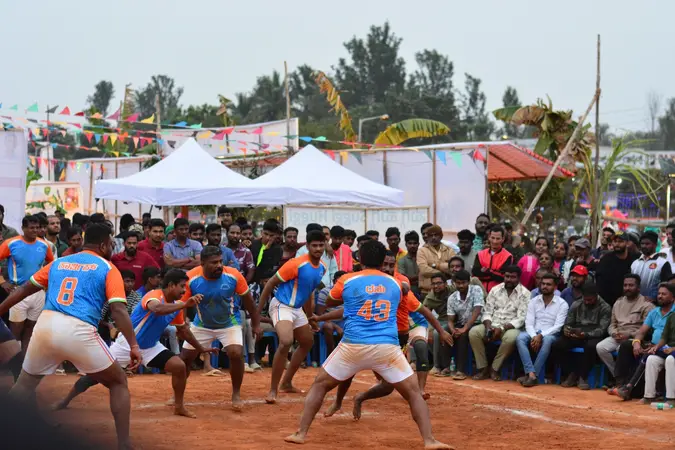 Kabaddi raiders and defenders mid-match on a mud court as a crowd watches
