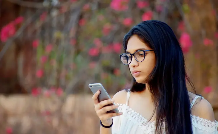 Young Indian woman reading on her smartphone outdoors
