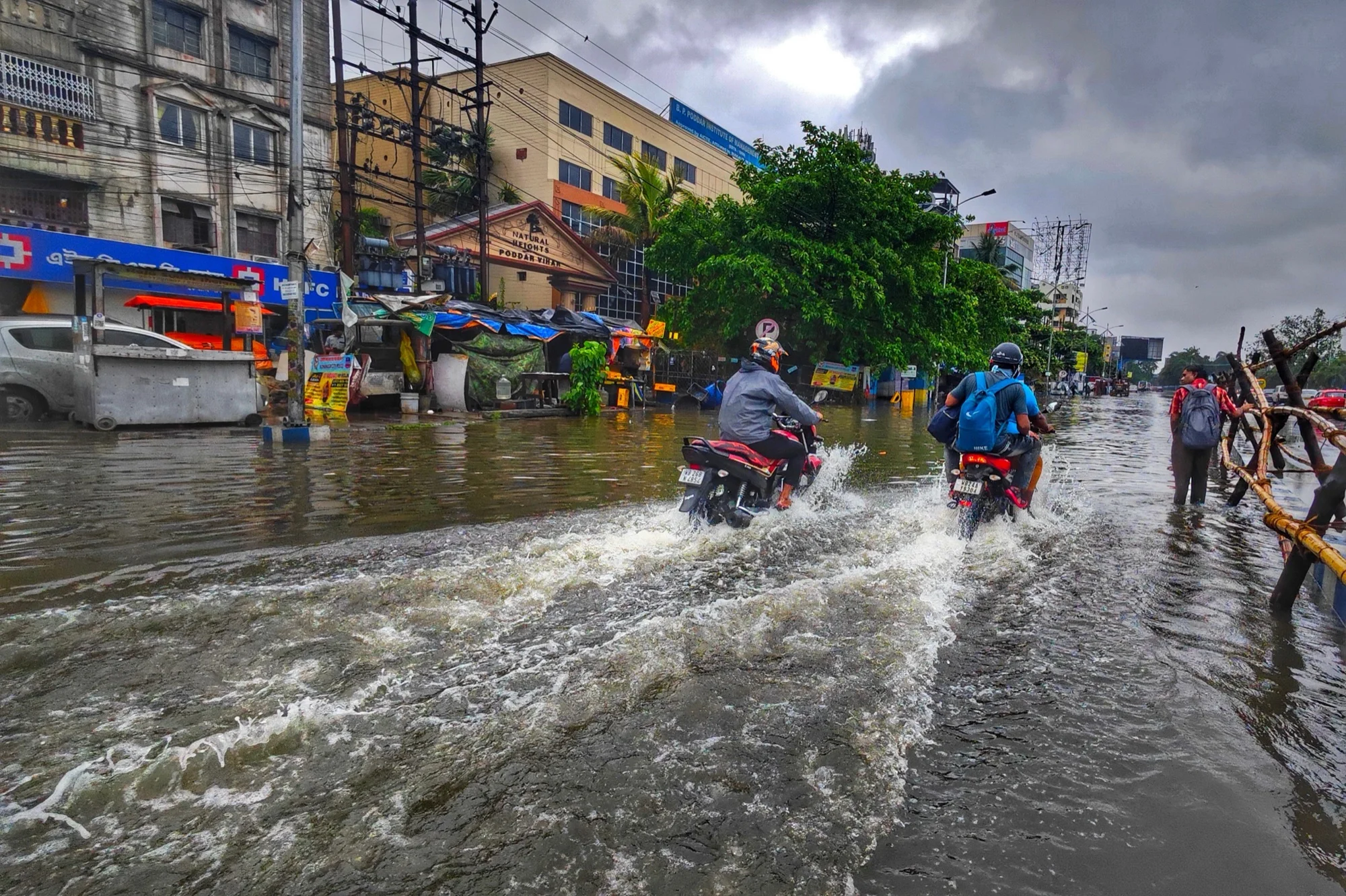 Motorcyclists riding through a flooded street in Kolkata during the monsoon