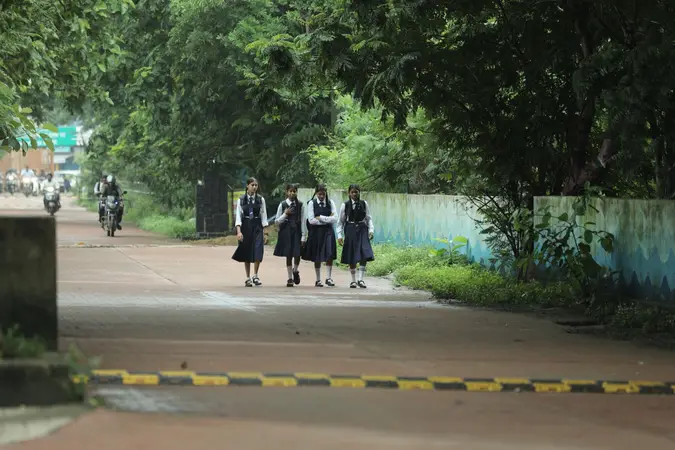 Four schoolgirls in uniform walking together down a tree-lined road in Raipur