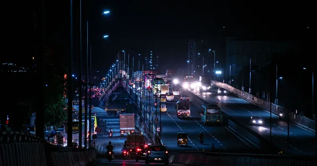 Night view of a busy highway bridge in India with streaks of moving traffic lights