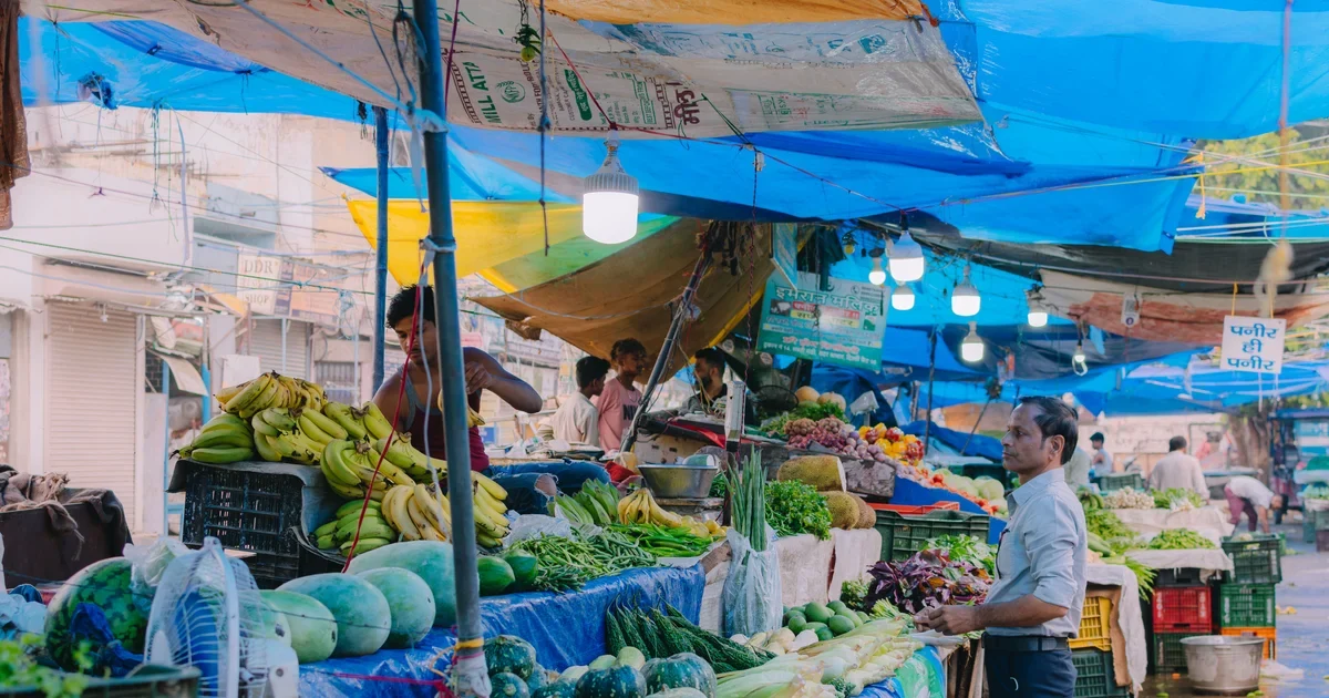 Fresh fruit and vegetable stalls under blue tarpaulins at a street market in India
