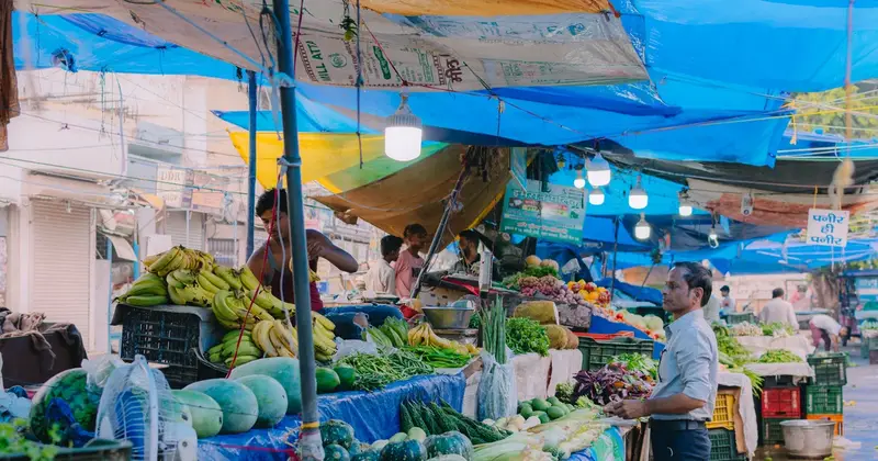 Fresh fruit and vegetable stalls under blue tarpaulins at a street market in India
