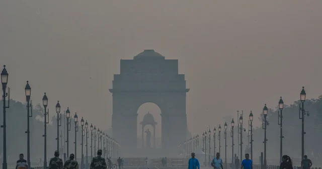 India Gate in New Delhi on a hazy morning with people walking nearby