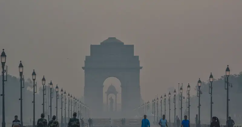 India Gate in New Delhi on a hazy morning with people walking nearby