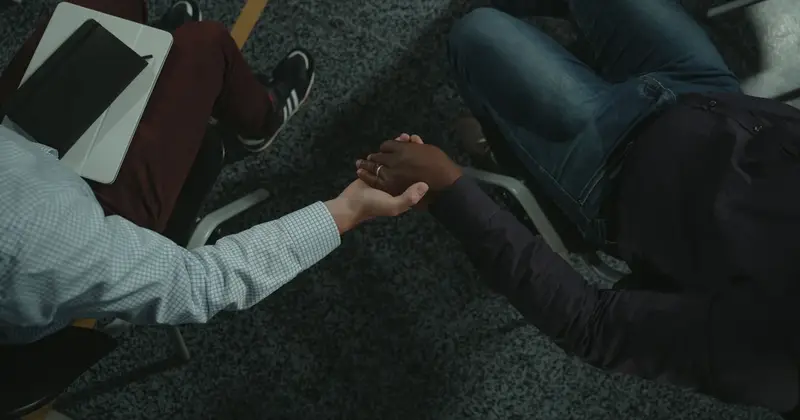 Two people shake hands during a counselling session, a first step towards treatment for addiction